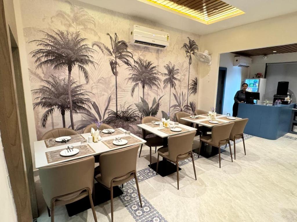 a restaurant with tables and chairs with palm trees on the wall at NE Heritage Residency in Guwahati