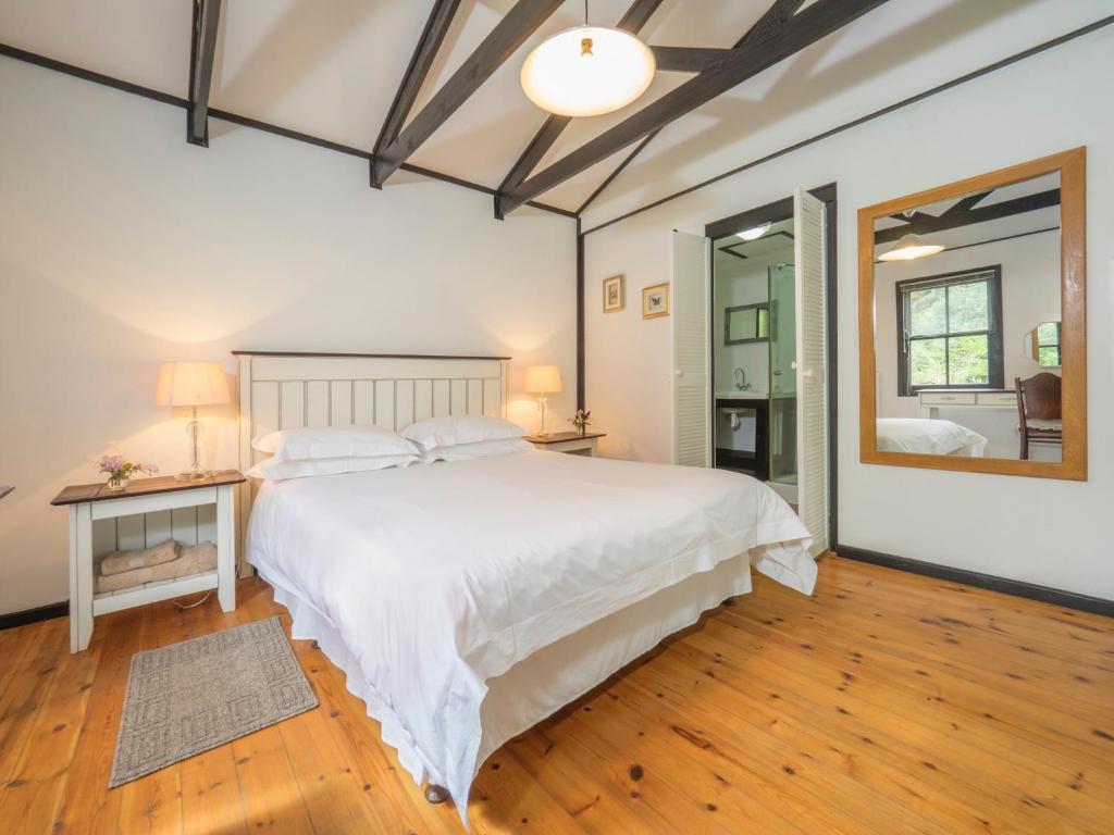 a bedroom with a large white bed and a mirror at Eagles' Call Cottages and Tent in Wilderness