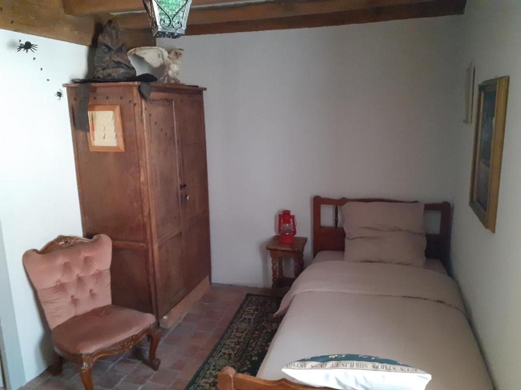 una piccola camera da letto con un letto e una sedia di Le terrier des sorciers a Crémieu