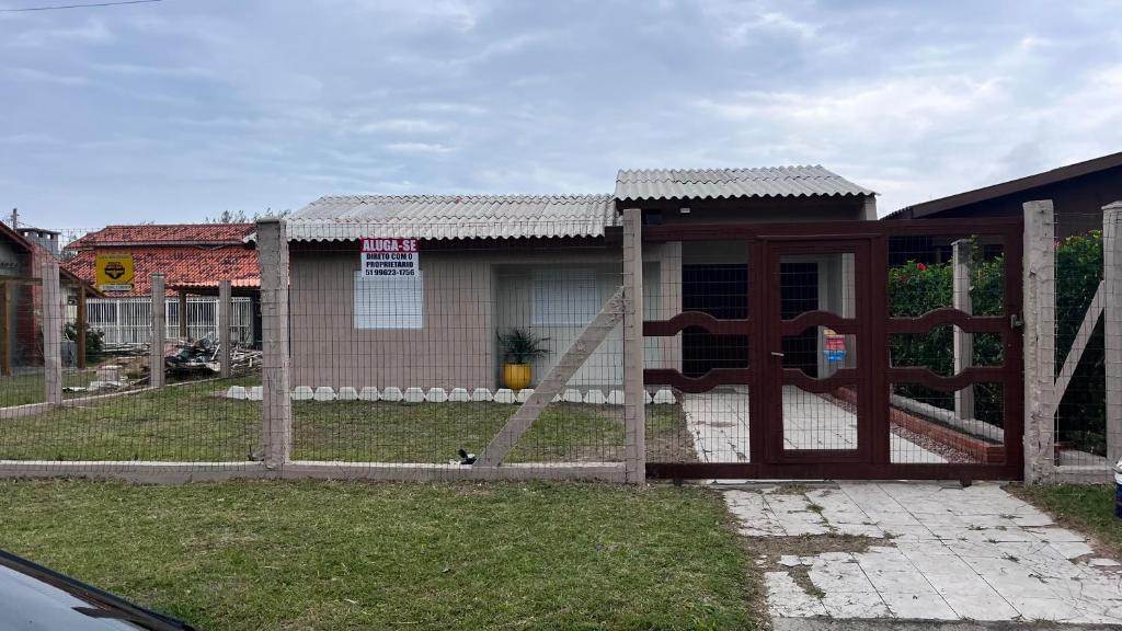 einen Zaun mit einem Tor vor einem Haus in der Unterkunft Linda casa para suas férias ! in Imbé