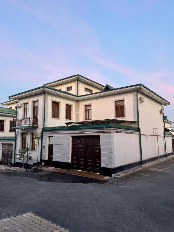 a large white building with a garage on a street at Town House in Samarkand