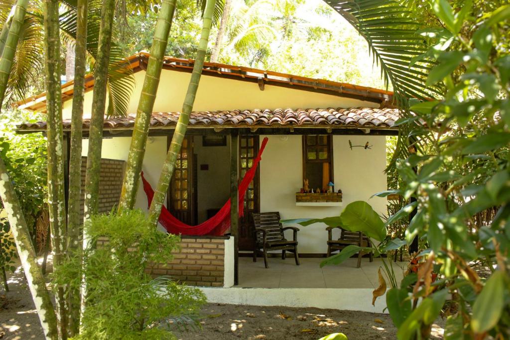 a house with a red curtain on the porch at Pousada Luar das Águas in Ilha de Boipeba