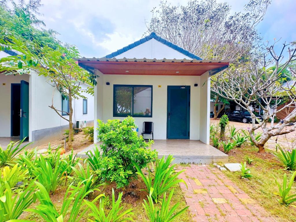 una pequeña casa blanca con una puerta azul en Khu Camping & Homestay Ven Biển, en Ấp Phước Tĩnh