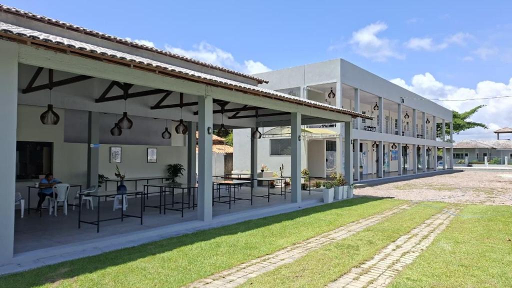 ein weißes Gebäude mit Tischen und Stühlen in einem Hof in der Unterkunft Asas da Maré Pousada in Bragança