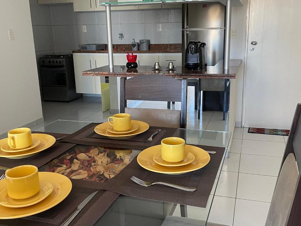 a kitchen with yellow cups and plates on a table at Apartamento Amplo - Ideal para famílias in João Pessoa
