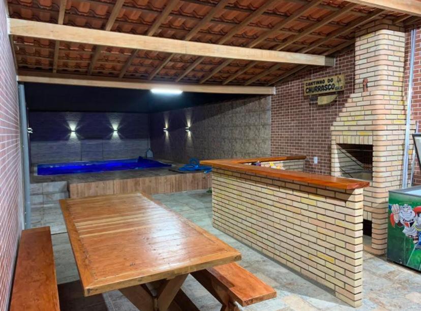 eine Küche mit einem Holztisch und einem Backsteinofen in der Unterkunft Sobrado com Piscina Oliveira in Mongaguá