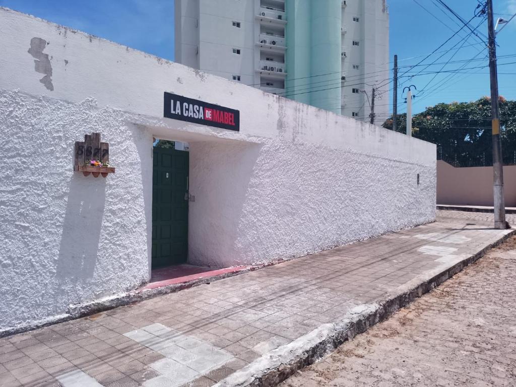 a white building with a green door and a sign on it at Hostel La Casa de Mabel in Natal