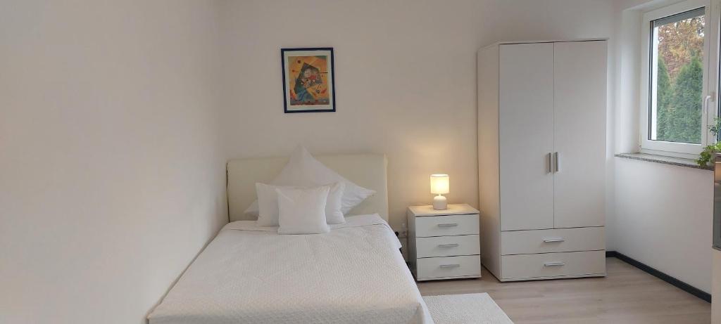 ein weißes Schlafzimmer mit einem Bett und einem Fenster in der Unterkunft Ferienwohnung in Großostheim