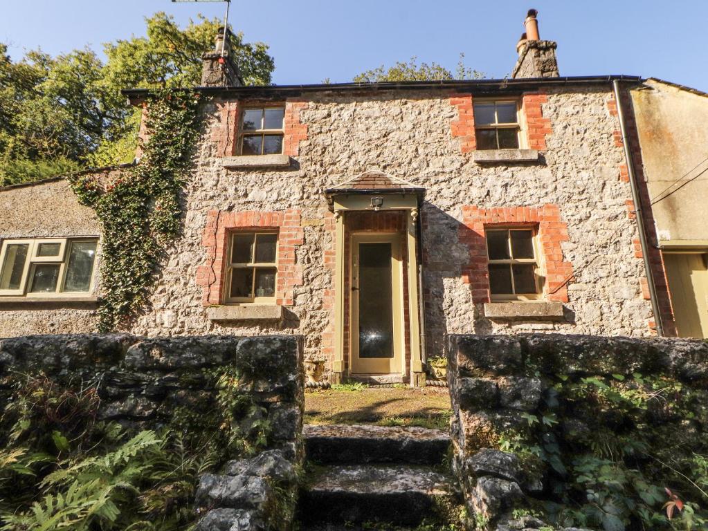 une ancienne maison en pierre avec un escalier en pierre en face de celle-ci dans l'établissement Rock Cottage, à Storth