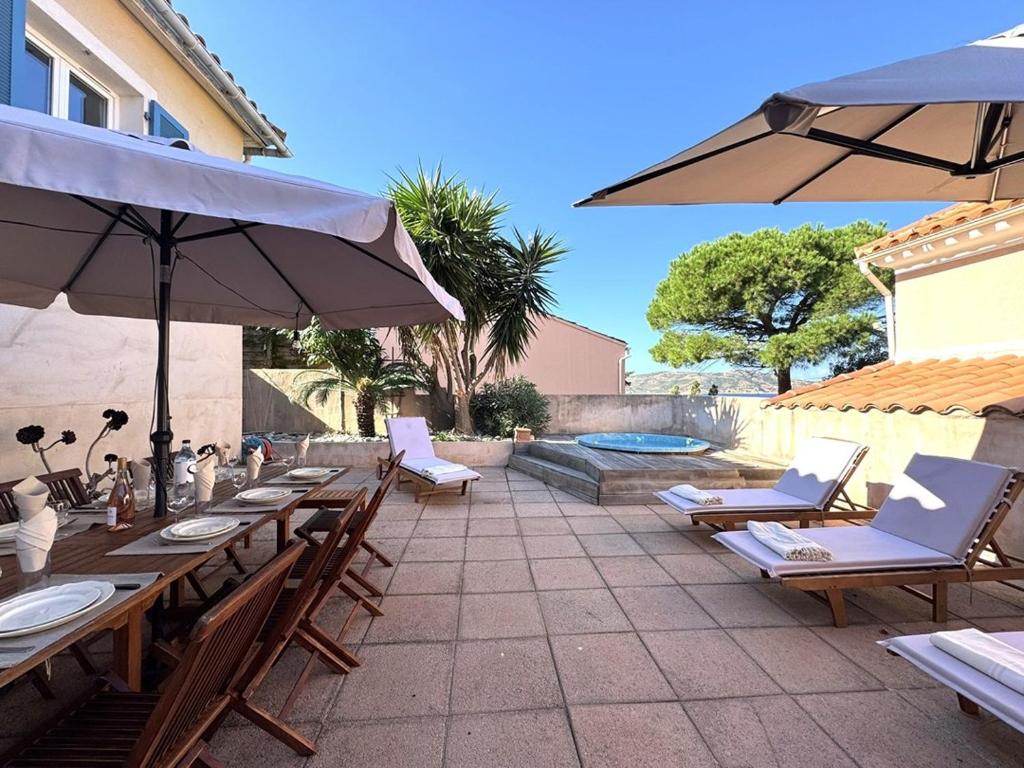 a patio with tables and chairs and an umbrella at Grande maison avec vue mer et jacuzzi au cœur de Calvi in Calvi