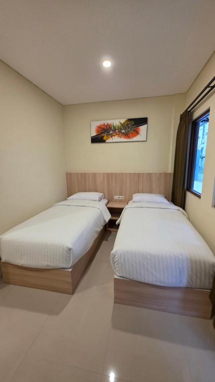 a bedroom with two beds and a window at M3 Sanur Hotel in Sanur