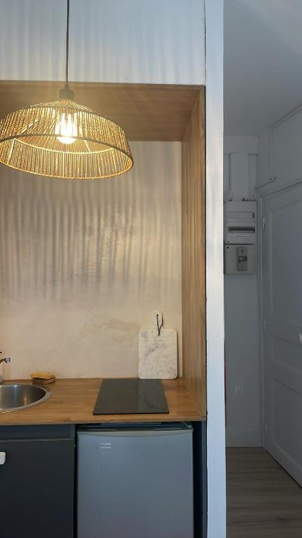 Una cocina con encimera con fregadero y luz. en Studio République, en Nantes