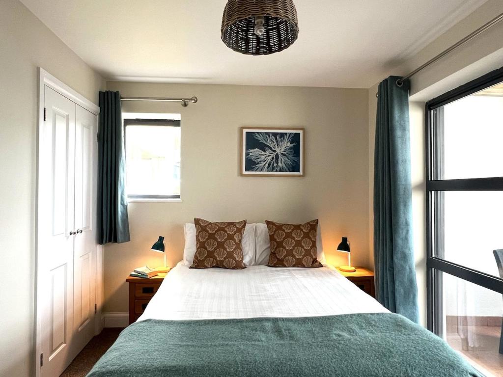 a bedroom with a bed and two windows at Deluxe Seaside Flat easy access in Westward Ho