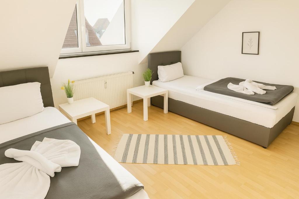 ein kleines Zimmer mit zwei Betten und zwei Tischen in der Unterkunft SUNNYHOME Monteurwohnungen und Apartments in Schwandorf in Schwandorf in Bayern