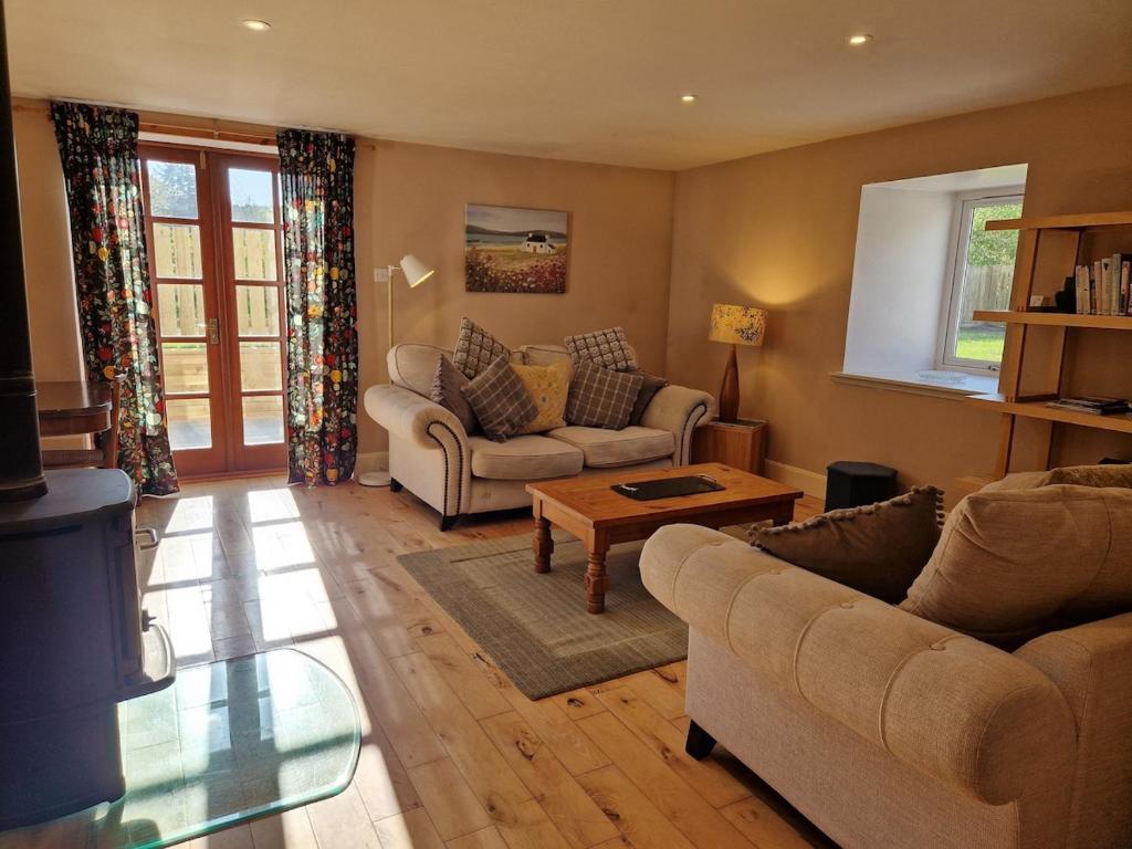 ein Wohnzimmer mit zwei Sofas und einem Couchtisch in der Unterkunft Highland River Cottage with Hot Tub in Evanton