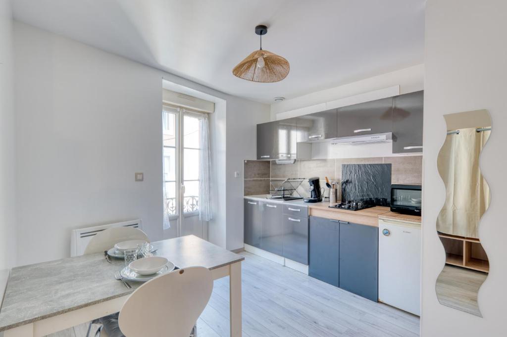Una cocina con gabinetes azules y una mesa y sillas. en Le Confort du Soir - T2 - Lagnieu, en Lagnieu