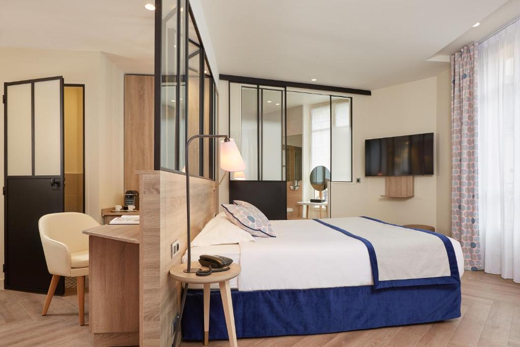 a hotel room with a bed and a desk and a chair at Hôtel de Sévigné in Paris