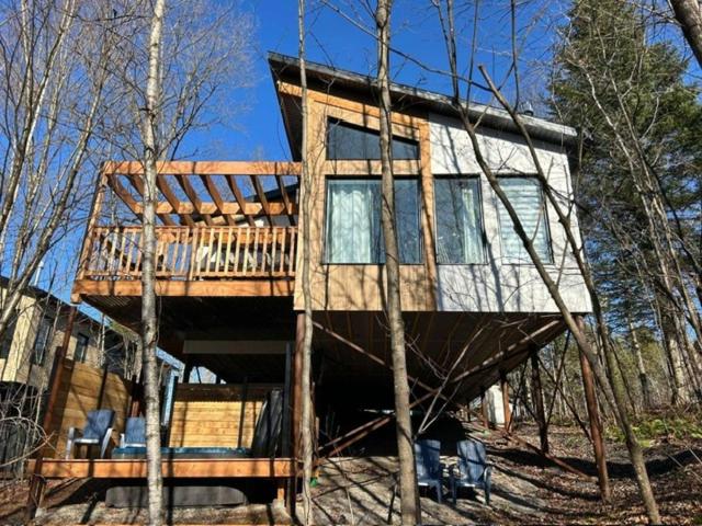 a tree house sitting in the middle of a forest at Chalet Arianna in Pont-Rouge