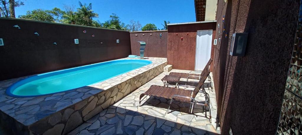 a swimming pool with two chairs next to a wall at Linda Casa de Praia com Piscina em Itapoá in Itapoa