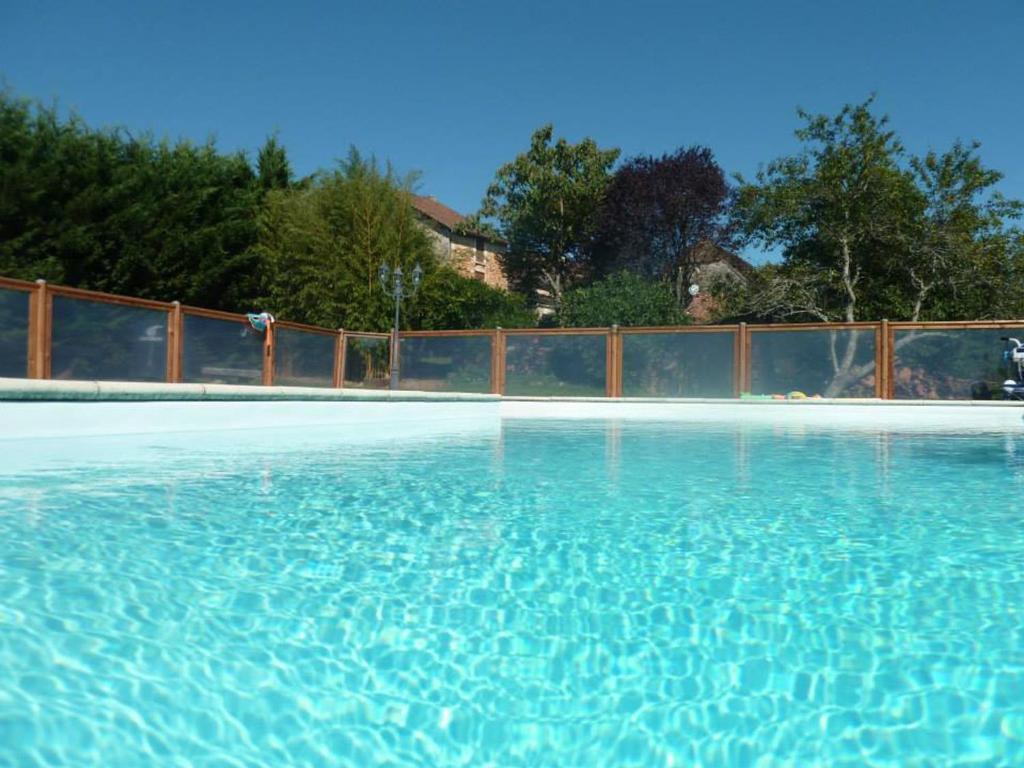 a swimming pool with blue water in front of a fence at La Closerie des Arts in Gabillou