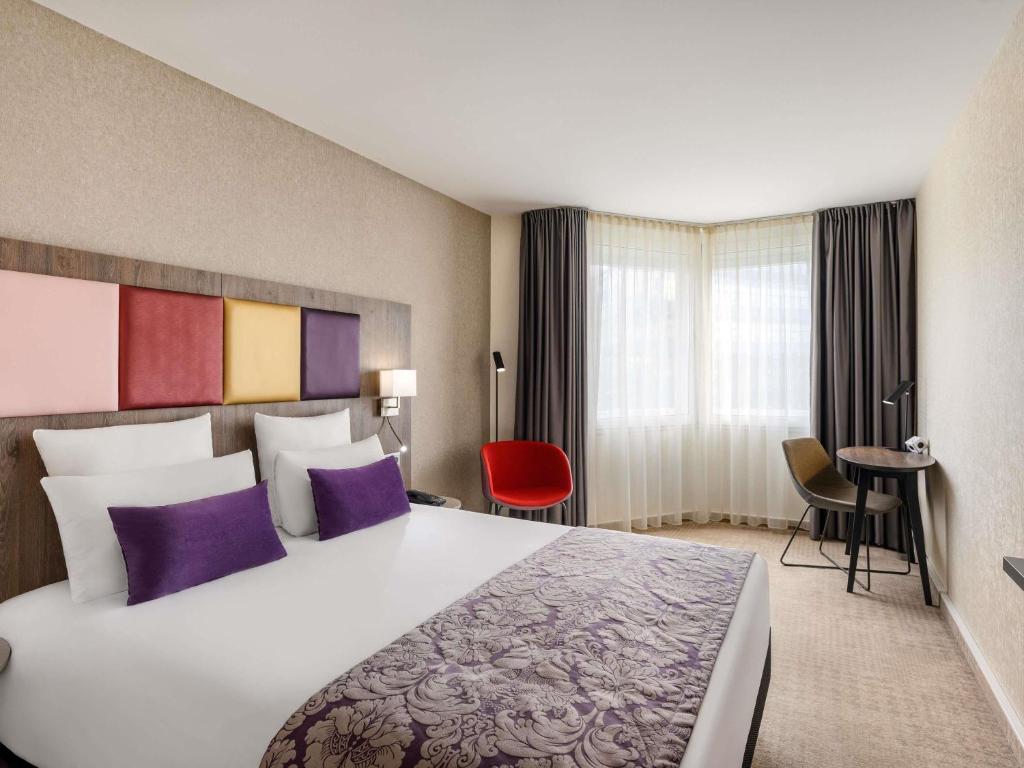 a hotel room with a large bed with purple pillows at Mercure Budapest Korona in Budapest