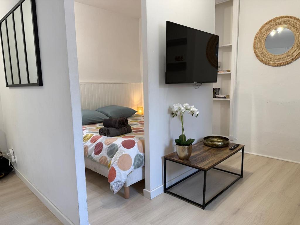 een slaapkamer met een bed en een tv aan de muur bij SWEET HOME Votre havre de paix au cœur d'Epernon in Épernon