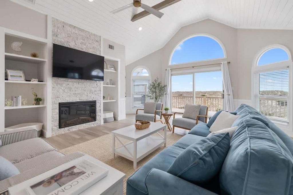 a living room with a blue couch and a fireplace at Elegant Updated Oceanfront Home with Pool & Hot Tub in Waves