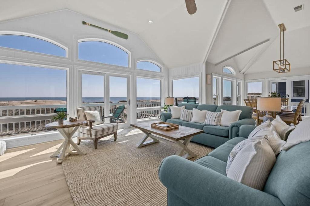 a living room with blue furniture and large windows at Blue Moon - LUX Oceanfront Pool Hot Tub Theater in Waves