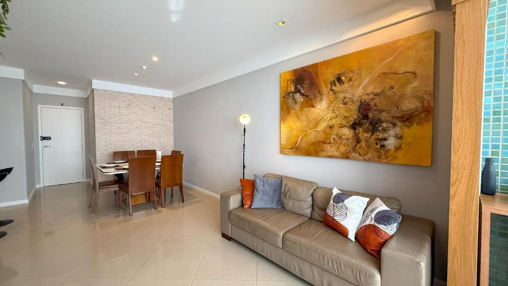 a living room with a couch and a dining room at RefugioBacutia- Prédio FRENTE MAR Bacutia- 6 pessoas- 3 Quartos com AR sendo 1 suite - varanda- sala de estar e jantar Ampla -Piscina e Sauna no Prédio in Guarapari