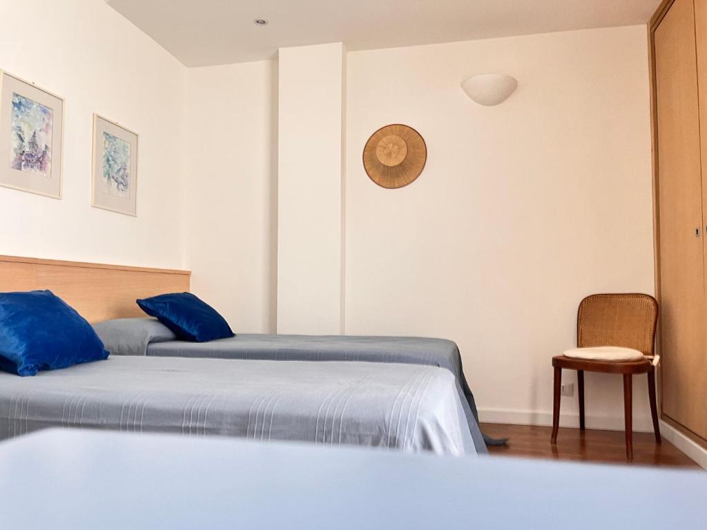 レトイアンニにあるMareluceのベッドが2つあり、壁に時計がある寝室