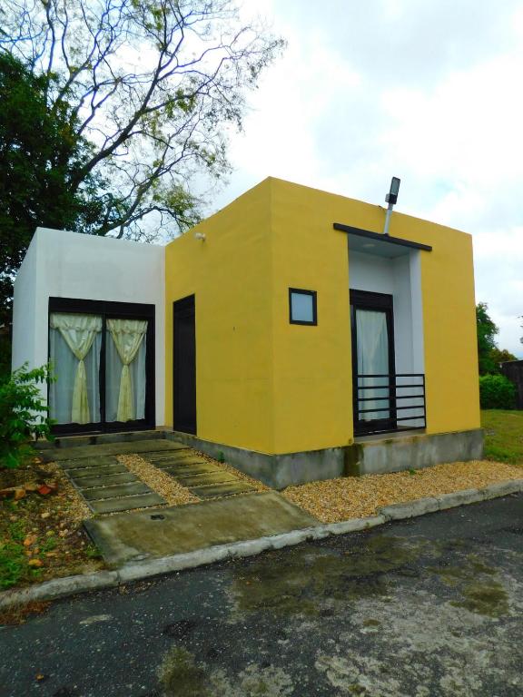a small yellow and white house on a street at Casa Vacacional - Portales del Sol 2 in Tocaima