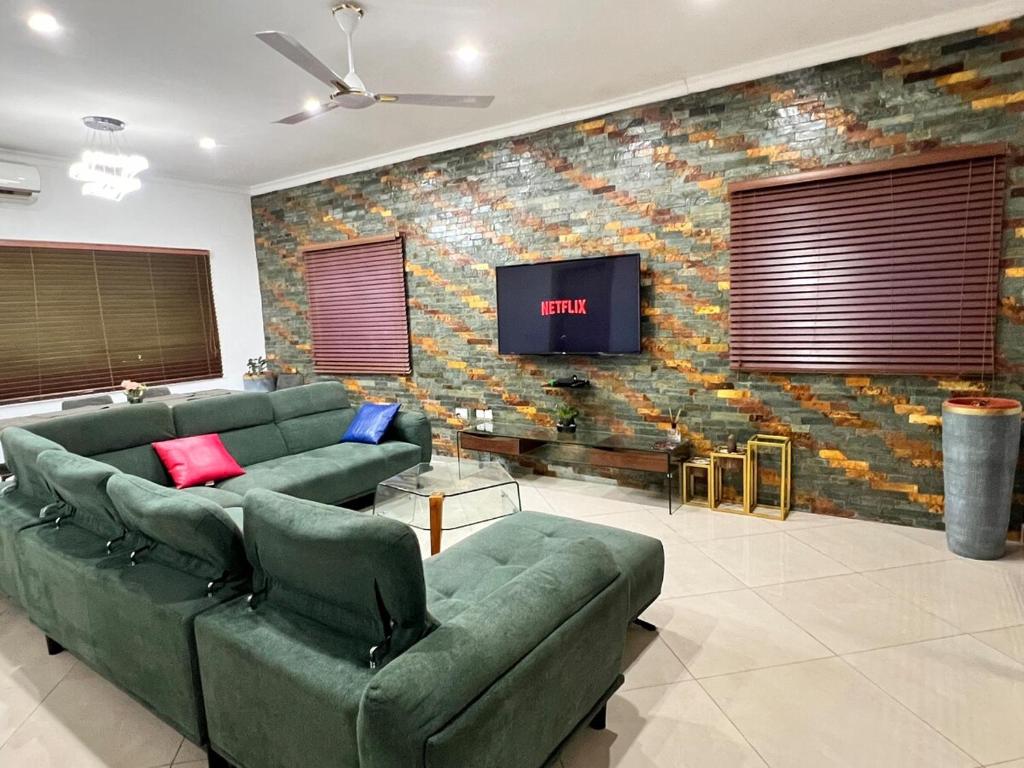 a living room with green couches and a brick wall at The Elegant 3BedRoom Home in Community 25, Tema in Dawhwenya