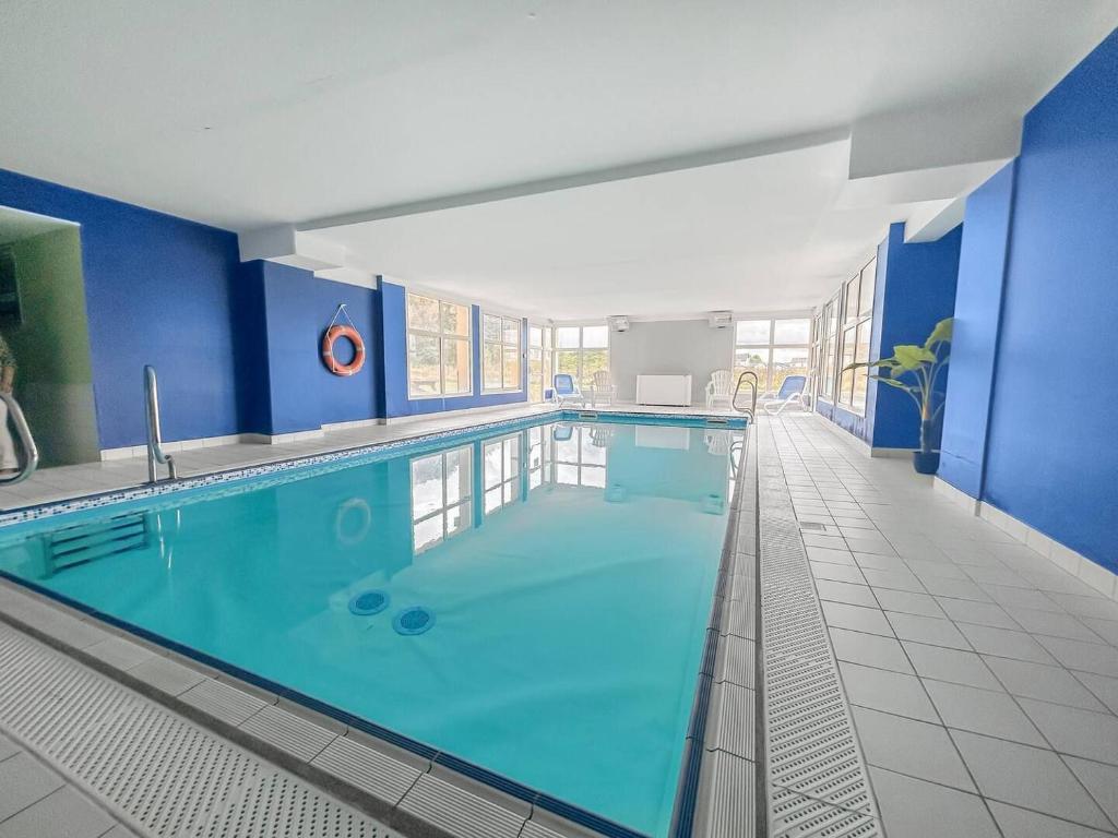 - une grande piscine dans un bâtiment aux murs bleus dans l'établissement Gîte Le 47, à Levernois