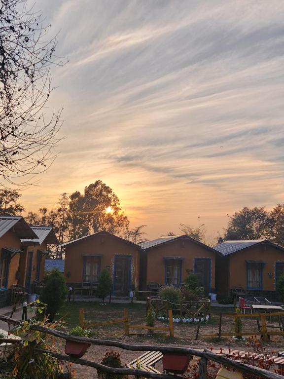 a row of houses with the sunset in the background at Monkey Mud House and Glamps, Bir in Bīr
