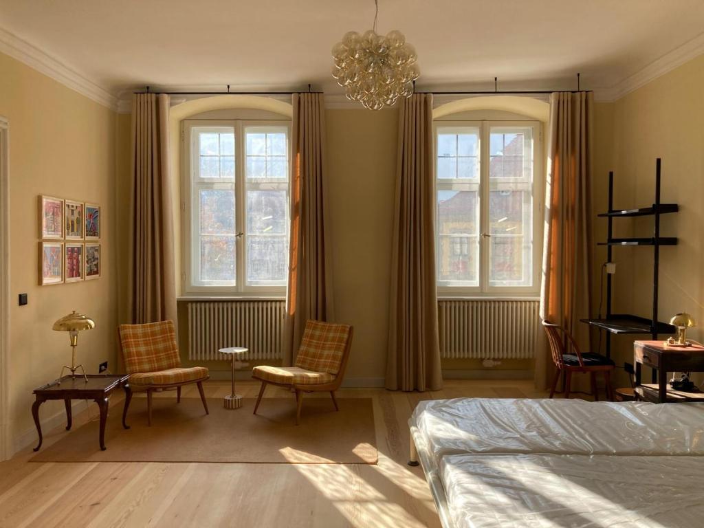 a bedroom with two windows and a bed and chairs at Schulze am Markt in Lichtenfels