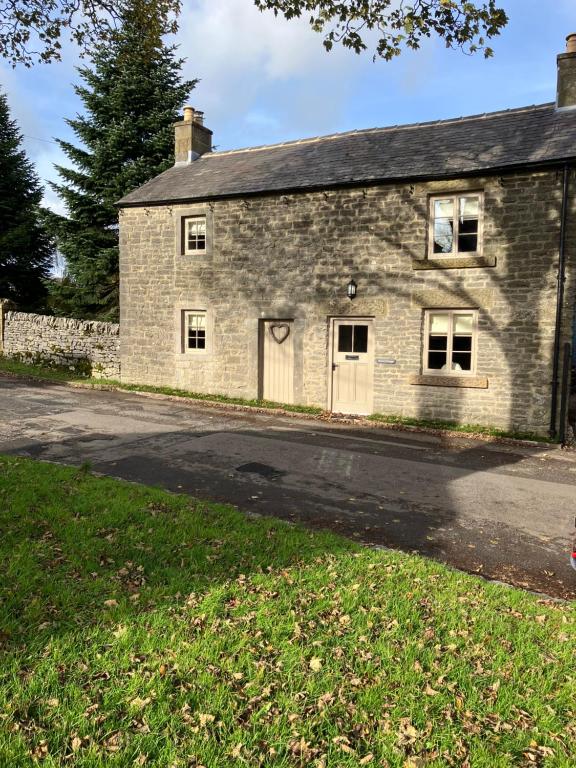 an old stone house with a road in front of it at Miners Cottage in Bakewell