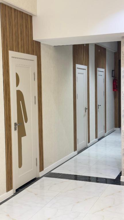 a row of doors in a hallway with a person sign on them at Arzum Hostel in Tashkent