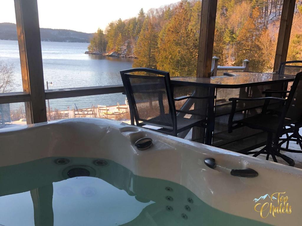 a bath tub with a view of the water at Front LAKE Simon HOT TUB 6br 17p BEACH private in Lac-Simon