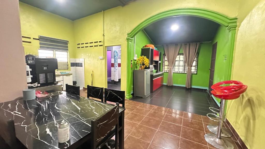 a kitchen with green and yellow walls and a red stool at D’sireh homestay in Sik