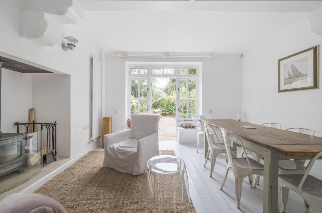 Brick Rose House في ويست ويتيرينغ: غرفة معيشة بيضاء مع طاولة وكراسي خشبية