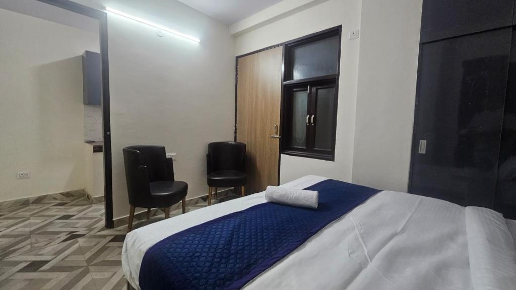 een slaapkamer met een bed en 2 zwarte stoelen bij Hotel Glass Castle Near Yashobhoomi in New Delhi