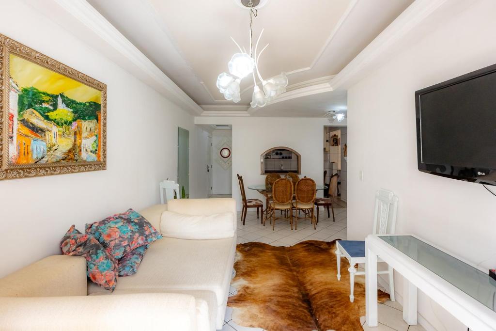 a living room with a couch and a flat screen tv at Apartamento com Varanda, Churrasqueira e Vista Mar in Meia Praia
