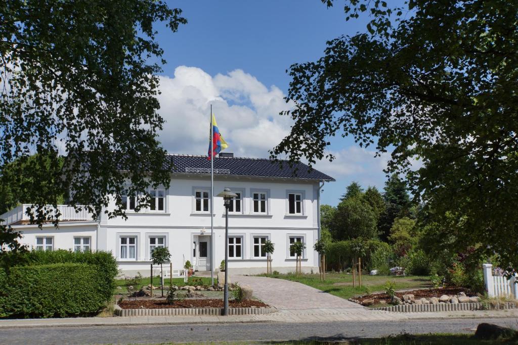 ein weißes Gebäude mit einer Flagge davor in der Unterkunft Haus Buddenbrock auf Rügen in Wiek auf Rügen 