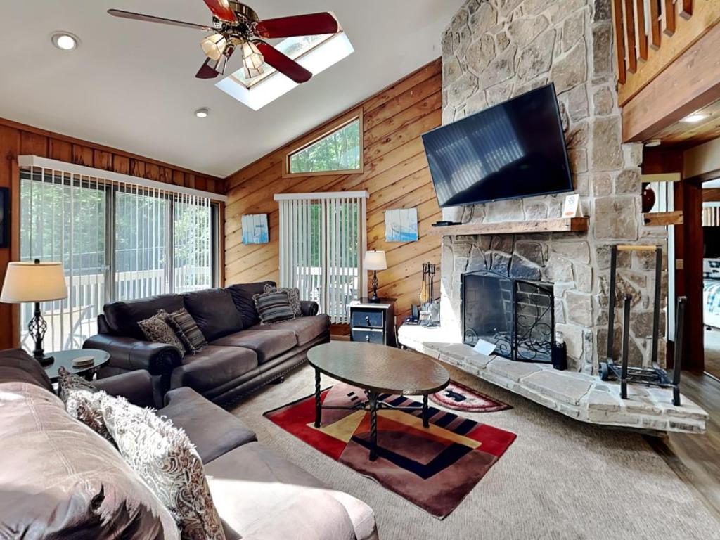 a living room with a stone fireplace and a tv at Cedar Ridge in Oakland