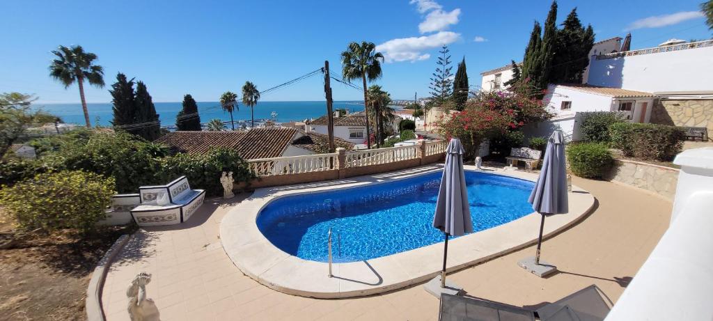 een zwembad met twee parasols en de oceaan bij Appartement Estaño in La Caleta