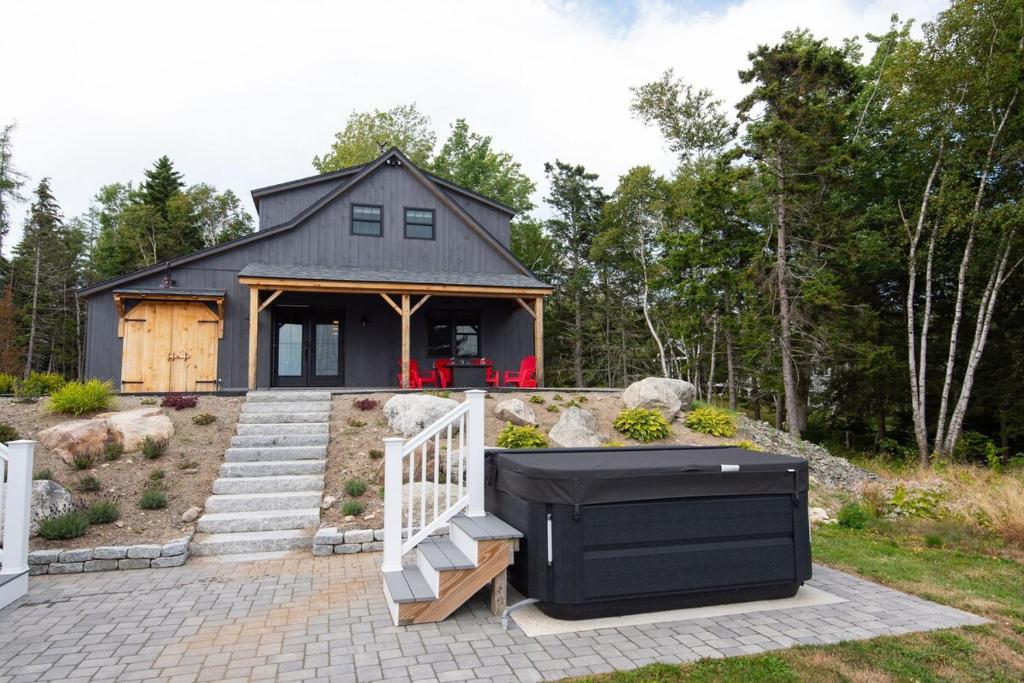 una pequeña casa negra con una escalera que conduce a ella en Oceanview Barnhouse Retreat with Hot Tub, en Steuben