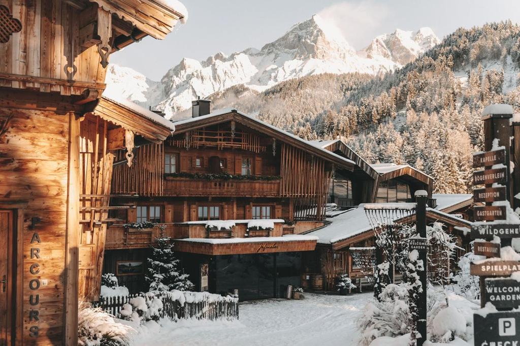een lodge in de sneeuw met bergen op de achtergrond bij Jufenalm BOHO & Wellnesshotel in Maria Alm am Steinernen Meer