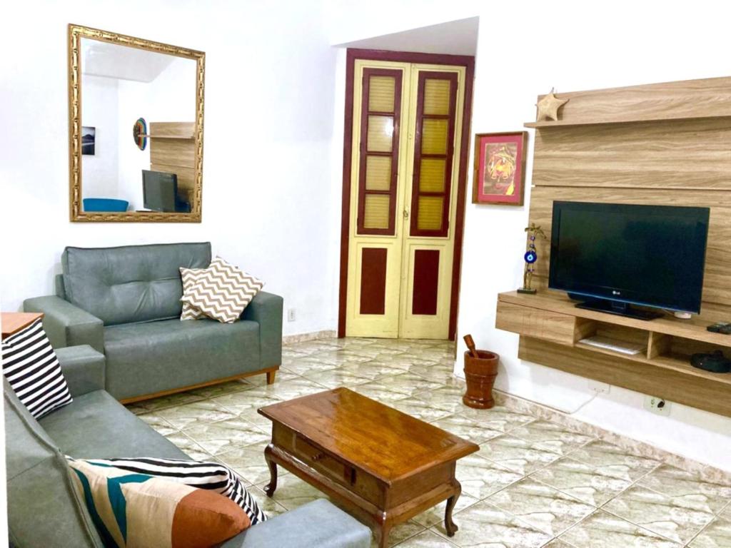 a living room with a couch and a tv at Edificio ALONE com terraço na quadra da praia, espaçoso e silencioso in Rio de Janeiro