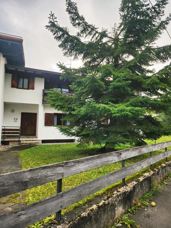 ein Holzzaun vor einem Haus mit einem Baum in der Unterkunft Margiolà in Calalzo