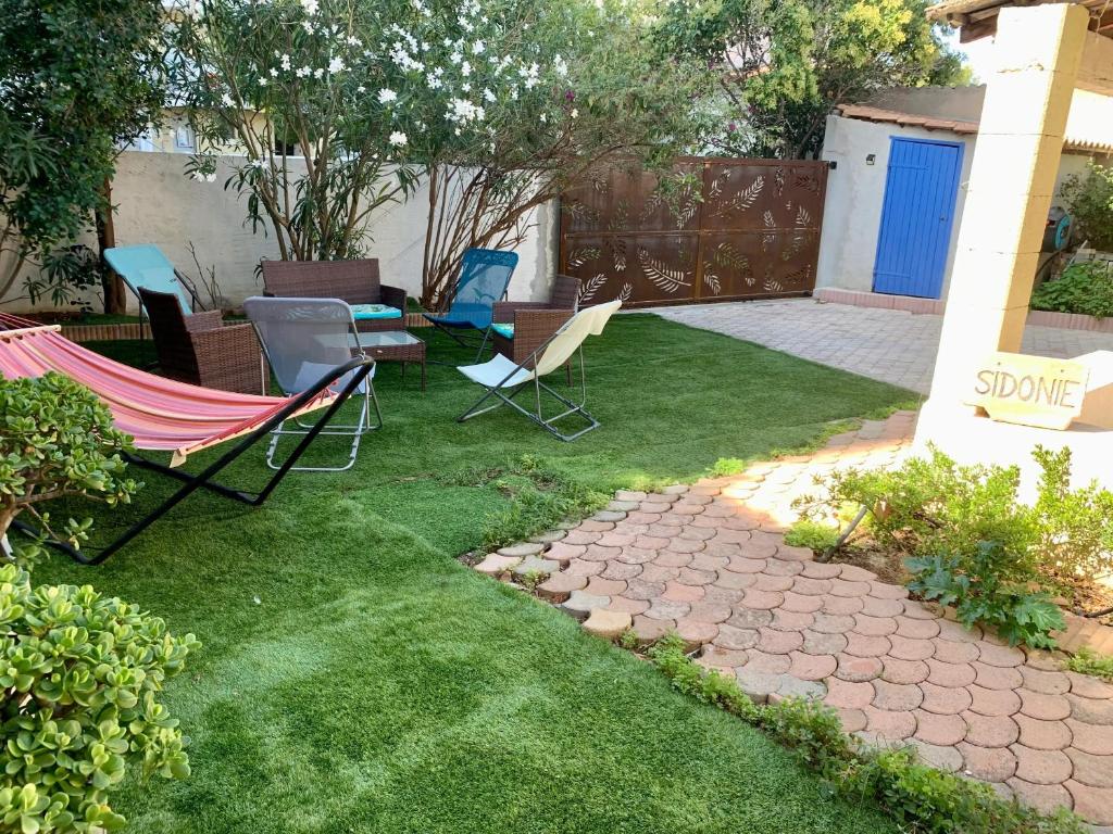 une cour avec des chaises et une terrasse avec pelouse dans l'établissement Maison confortable avec jardin à Marseille, à Marseille